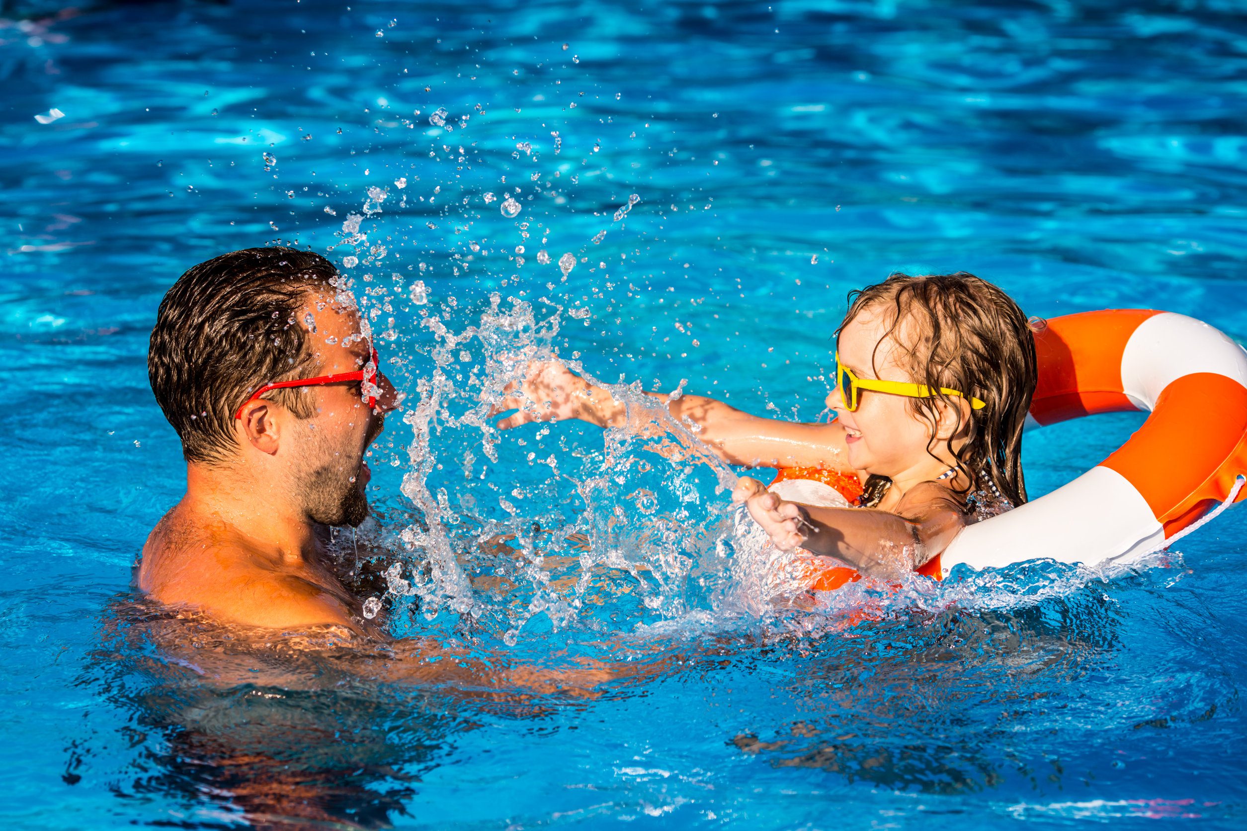 Child and father playing in swimming pool